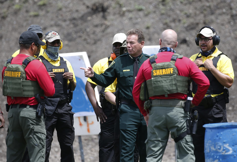 In this Monday, July 30, 2018 photo, Broward County Sheriff Scott Israel, center, talks with trainers and Broward County Public Schools newly-hired armed guardians during firearms training at BSO's gun range at Markham Park in Sunrise, Fla. Twenty-two of the Florida school districts are supplementing officers with "guardians" -- armed civilians or staff. They are vetted, receive 132 hours of training and must attain a higher score on the state firearms test than rookie police officers. (AP Photo/Wilfredo Lee)