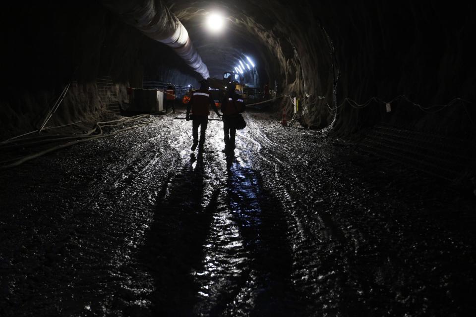 In this Sept. 25, 2012 photo, workers from the National Copper Mine Corporation, or Codelco, walk through a tunnel drilled under the Chuquicamata copper mine in the Atacama desert in northern Chile. Experts say that by 2019 the Chuquicamata copper mine will be unprofitable, so state-owned mining company Codelco is trying to head off closure by converting the open pit into the world's largest underground mine. Codelco believes the mine still has much more to give, with reserves equal to about 60 percent of all the copper exploited in the mine's history still buried deep beneath the crater. (AP Photo/Jorge Saenz)