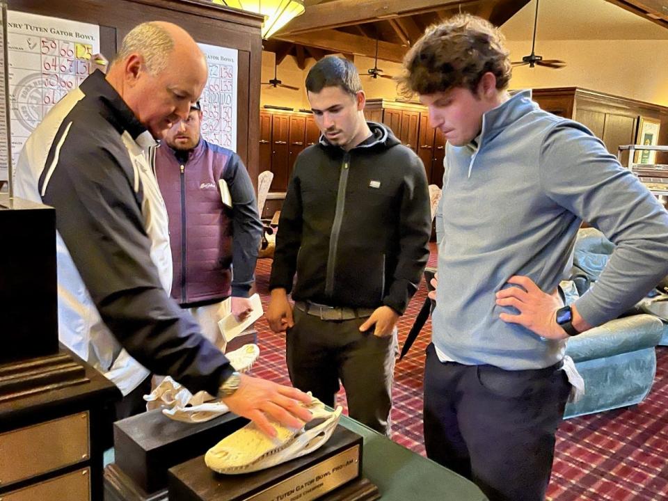 Henry Tuten Gator Bowl Pro-Am committee member John Brooks (left) shows Scott Kennon (center) and Andrew McLauchlan (right) the trophies they would receive as part of the winning team in the 2022 tournament.