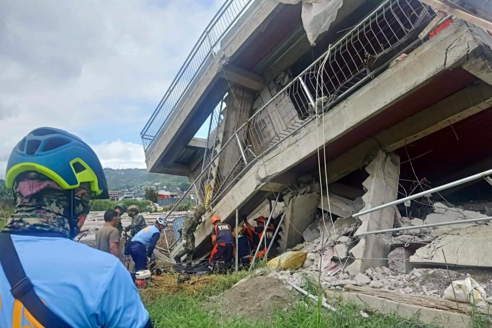In this handout photo provided by the Bureau of Fire Protection, rescuers try to pull out a trapped resident from under a collapsed structure after a strong earthquake struck La Trinidad, Benguet province, northern Philippines on Wednesday July 27, 2022. A strong earthquake left some people dead and injured dozens in the northern Philippines on Wednesday, where the temblor set off small landslides and damaged buildings and churches and prompted terrified crowds and hospital patients in the capital to rush outdoors.