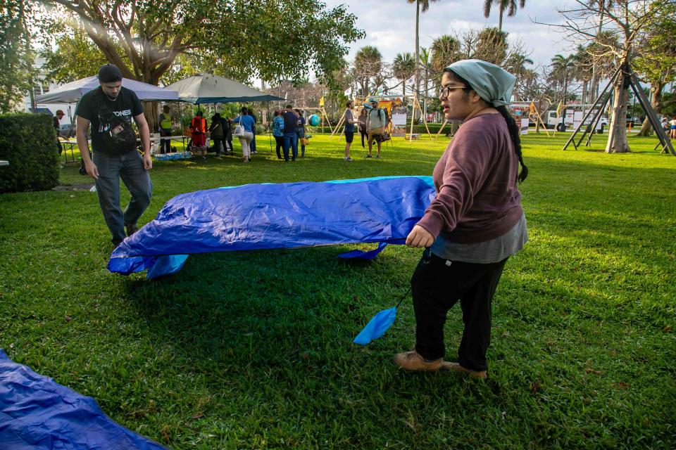 Miami resident Janet Morales spreads a tarp out in the grass at Bradley Park on Sunday.