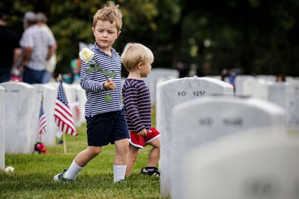 Young boys place roses at the final resting place of fallen service members in Arlington National Cemetery on Memorial Day.