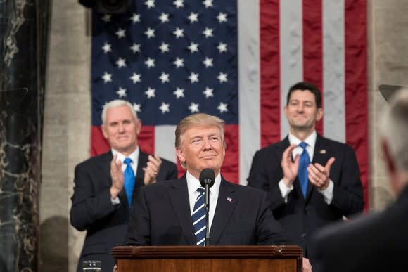 Donald Trump at a podium with Vice President Mike Pence and Speaker of the House Paul Ryan standing behind him.