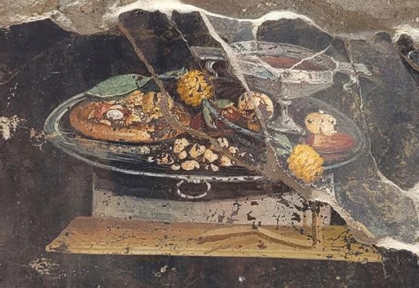 Picture provided on June 27, 2023, by the Pompeii Archaeological Park shows the wall of an ancient Pompeian house with a fresco depicting a table with food. The fresco was found in the atrium of a house under excavation to which a bakery was annexed, already partially explored between 1888 and 1891 and whose investigations were resumed last January.  / Credit: Pompeii Archaeological Park via AP