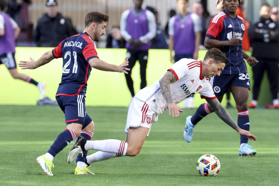 Toronto FC forward Federico Bernardeschi, right, gets tripped by new England Revolution midfielder Nacho Gil, left, in the second half of an MLS soccer match, Sunday, March 3, 2024, in Foxborough, Mass. (AP Photo/Mark Stockwell)