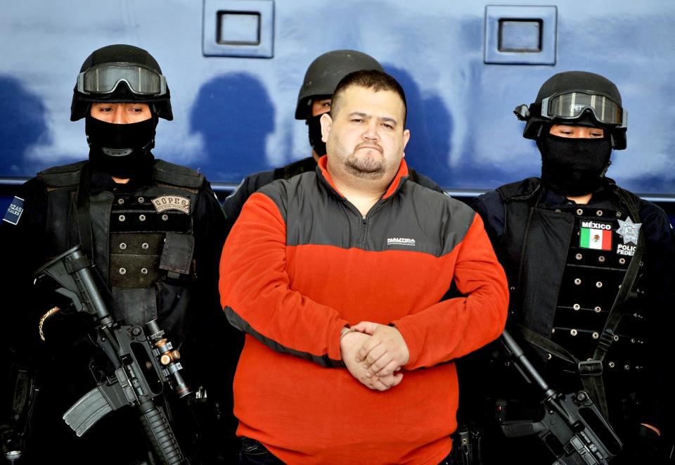 Eduardo Teodoro Garcia Simental, a.k.a "El Teo" (C), one of Mexico's most-wanted drug lords with possible connections to the Arellano Felix brothers or Tijuana cartels, is seen guarded by police officers in Mexico City on January 12, 2010. Garcia was captured early on January 12, 2010 in the northwestern state of Baja California Sur, Mexico, along with one of his brothers known as 'El Torito'. AFP PHOTO/Alfredo ESTRELLA (Photo credit should read ALFREDO ESTRELLA/AFP via Getty Images)