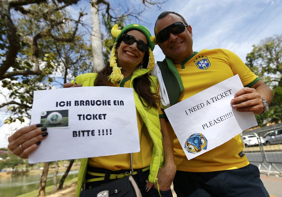 Brazilian fans searching for tickets for semi-final match Brazil against Germany hold placards ouside Estadio Mineirao in Belo Horizonte