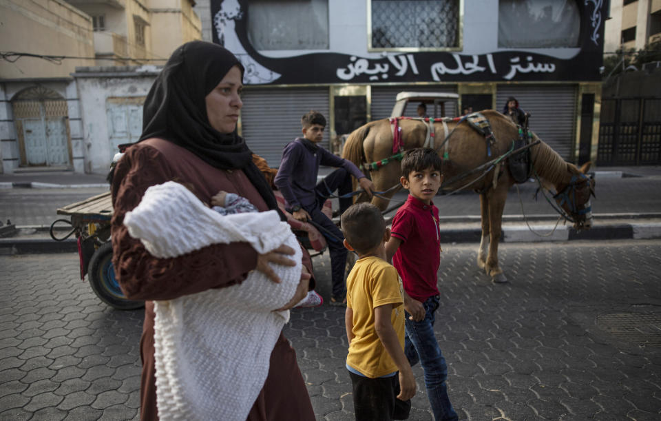 Palestinians flee their homes after overnight Israeli heavy missile strikes on their neighborhoods in the outskirts of Gaza City, Friday, May 14, 2021. (AP Photo/Khalil Hamra)