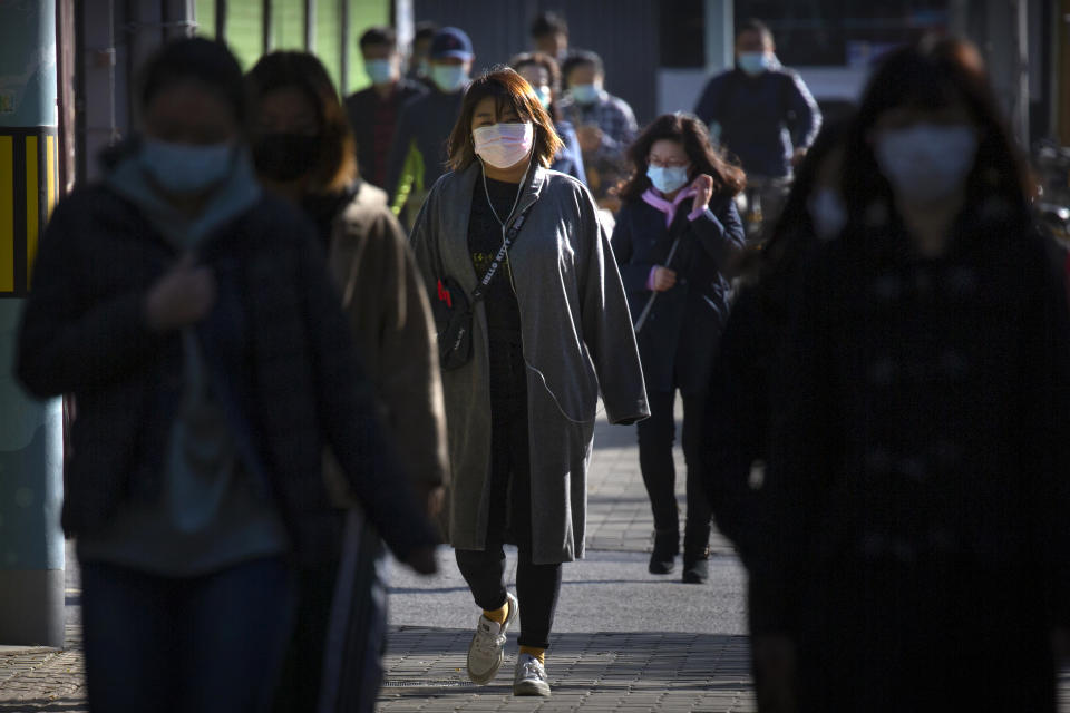 Commuters wearing face masks to protect against the coronavirus walk along a street in Beijing, Thursday, Oct. 22, 2020. The number of confirmed COVID-19 cases across the planet has surpassed 40 million, but experts say that is only the tip of the iceberg when it comes to the true impact of the pandemic that has upended life and work around the world. (AP Photo/Mark Schiefelbein)