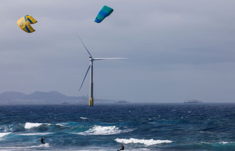 FILE PHOTO: Two sportsmen sail near an offshore wind turbine of the Siemens Gamesa company is seen from the Telde coast on the island of Gran Canaria