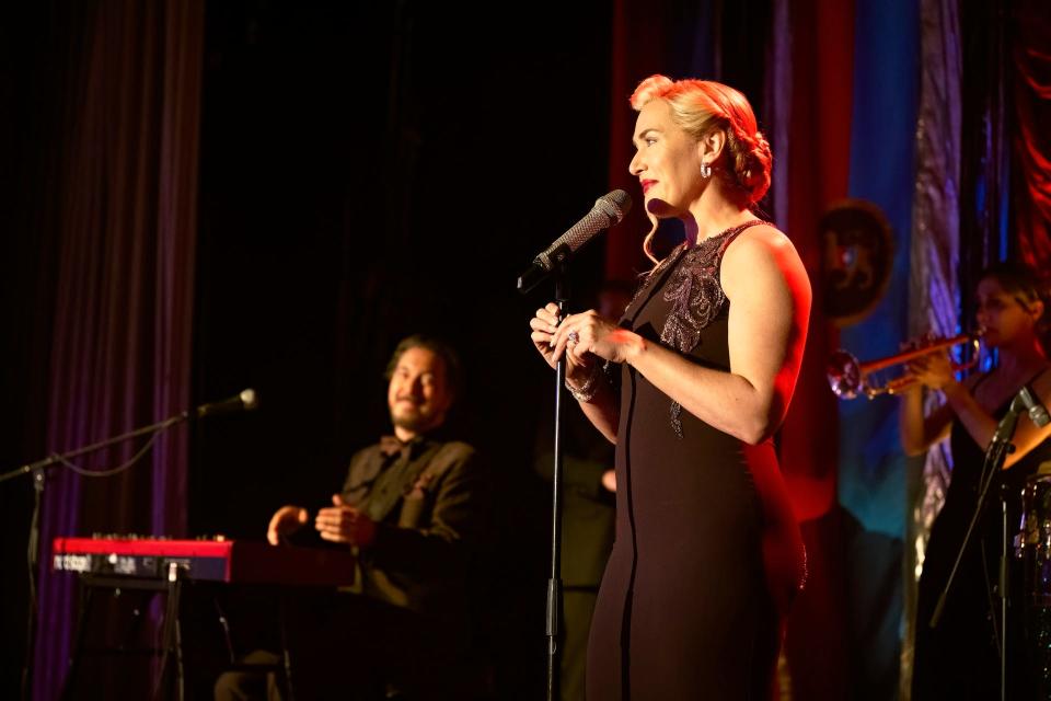 Elena (Kate Winslet, right) is accompanied on keyboard by husband Nicholas (Guillaume Gallienne) during her performance.