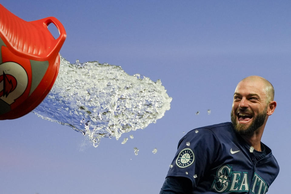 Seattle Mariners' Mitch Haniger tries to avoid a dousing during the celebration of the team's 2-1 win over the Chicago White Sox in 10 innings in a baseball game Wednesday, June 12, 2024, in Seattle. Haniger drove in the winning run. (AP Photo/Lindsey Wasson)