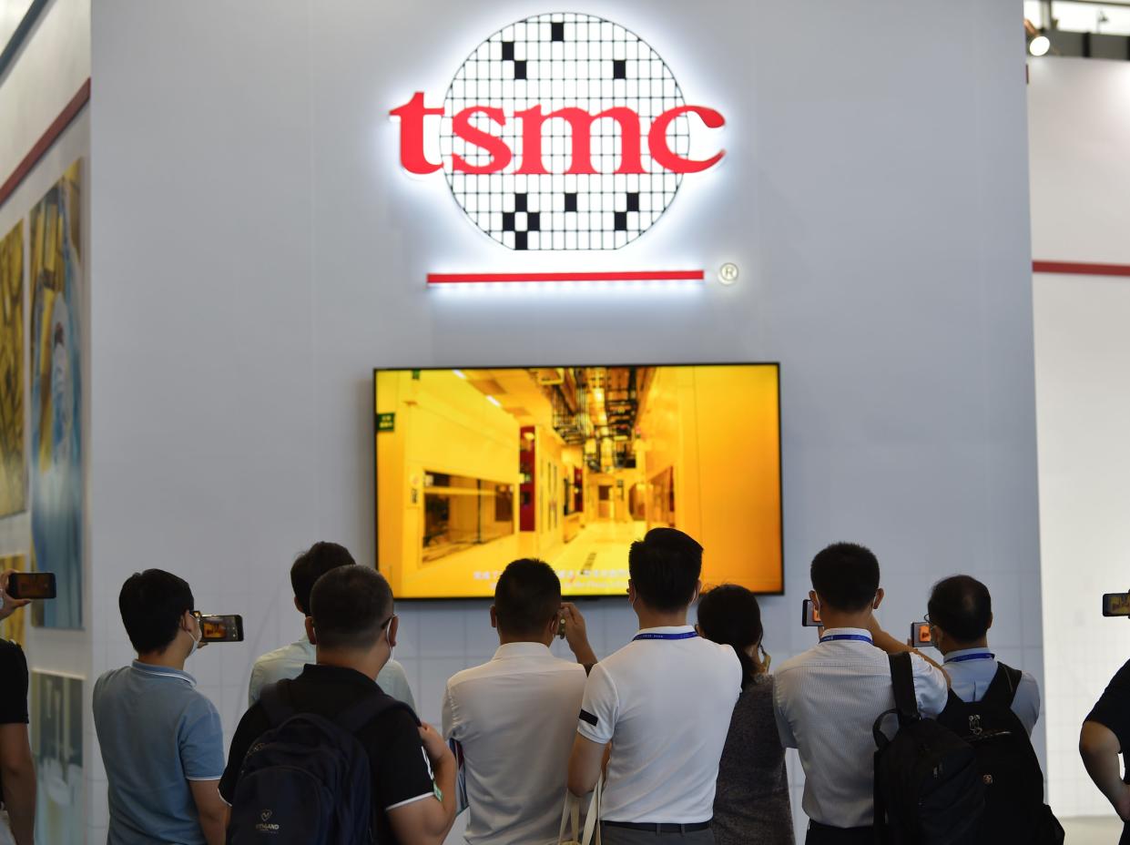 People looking at TV screen with logo of Taiwanese chipmaker TSMC above.