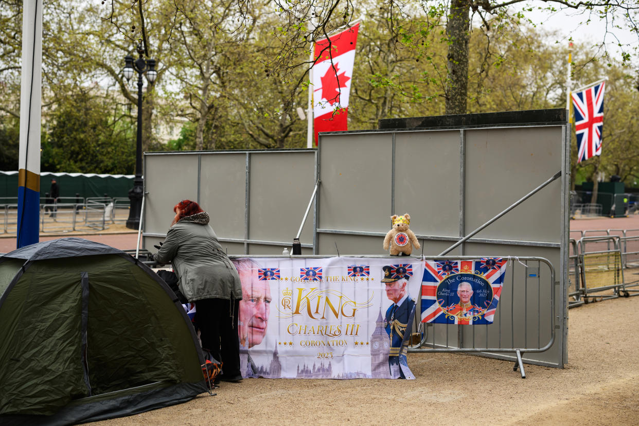 LONDON, ENGLAND - MAY 02: A woman stands near to her temporary camp next to flags displayed featuring King Charles III on the route of the Coronation near Buckingham Palace on May 02, 2023 in London, England. The Coronation of King Charles III and The Queen Consort will take place on May 6, part of a three-day celebration. (Photo by Leon Neal/Getty Images)