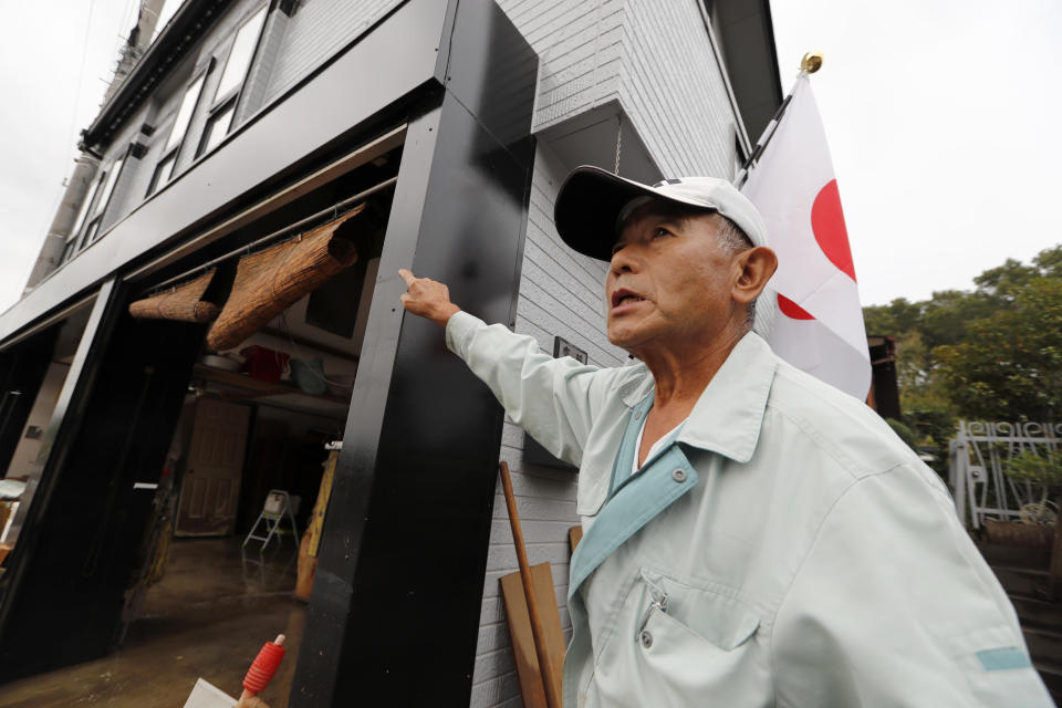 CORRECTS NAME - Kazuo Saito shows the flood water level of his house as he cleans up Monday, Oct. 14, 2019, in Kawagoe City, Japan. Typhoon Hagibis dropped record amounts of rain for a period in some spots, according to meteorological officials, causing more than 20 rivers to overflow. Some of the muddy waters in streets, fields and residential areas have subsided. But many places remained flooded, with homes and surrounding roads covered in mud and littered with broken wooden pieces and debris. (AP Photo/Eugene Hoshiko)
