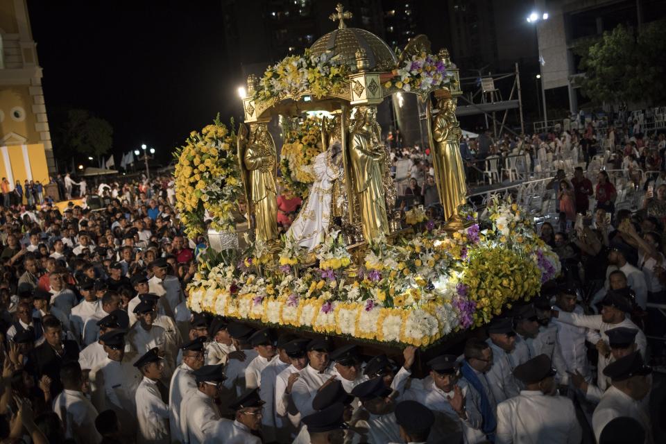 In this Nov. 18, 2019 photo, faithful referred to as "Servidores Mañaneros" or morning servers, carry the image of the Virgin of Chiquinquira during a procession, in Maracaibo, Venezuela. Thousands of Venezuelans flocking to Maracaibo’s ornate basilica each year at this time traditionally ask for help overcoming illness or conceiving a child. But many faithful say a crisis driving the exodus of millions has made them ask for something bigger than themselves. (AP Photo/Rodrigo Abd)