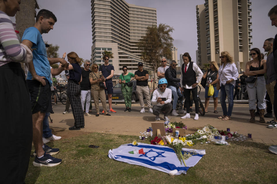 People gather and lay flowers at the site where Alessandro Parini, an Italian tourist, was killed in a Palestinian attack, in Tel Aviv, Israel, Saturday, April 8, 2023. Israeli authorities said an Italian tourist was killed and five other Italian and British citizens were wounded Friday when a car rammed into a group of tourists in Tel Aviv. (AP Photo/Oded Balilty)