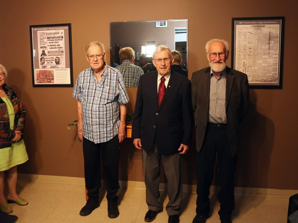 Louise Imbeault, former editor of L‘Évangéline, Léo-Paul Léger, member of the Moncton Press Club, Bernard Poirier, president of the committee of former employees, and Ross MacKay, interim president of the Moncton Press Club, stand in front of the framed pages unveiled Saturday. (Normand A. Léger - image credit)