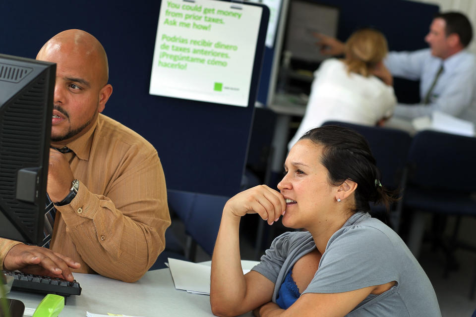 Boris Rios (L), H&R Block Tax Associate Office Manager, works on Margarita Gambetta's tax form the day before the Internal Revenue Service deadline in Miami Beach, Florida.  (Credit: Joe Raedle/Getty Images)