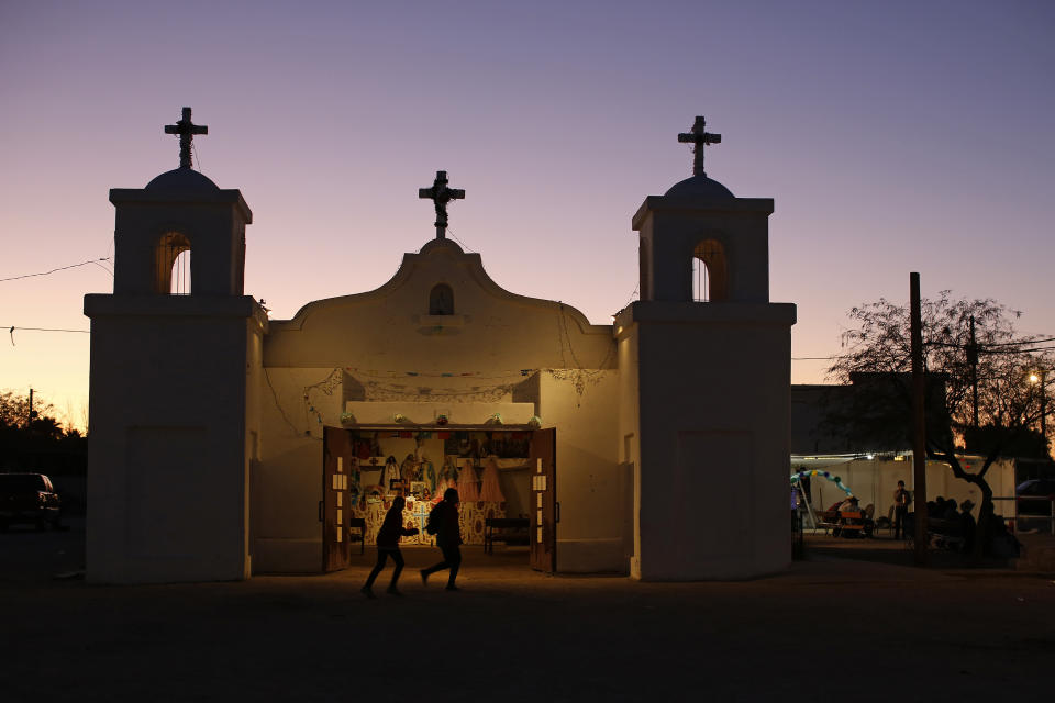 In this Feb. 8, 2020, photo, two children run past the Our Lady of Guadalupe church in the town of Guadalupe, Ariz., near Phoenix. Founded by Yaqui Indian refugees from south of the border more than a century ago, the town named for Mexico's patron saint, is proud of its history but wary of outsiders as it prepares for the 2020 Census count its leaders hope will help better fund a $12 million budget to fill potholes and mend aging sewage lines. (AP Photo/Dario Lopez-MIlls)