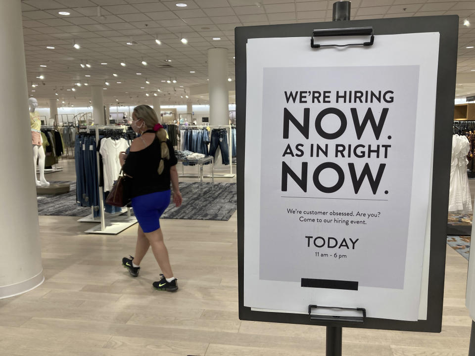 A customer walks behind a sign at a Nordstrom store seeking employees, Friday, May 21, 2021, in Coral Gables, Fla. The number of Americans seeking unemployment benefits dropped last week to 406,000, a new pandemic low and more evidence that the job market is strengthening as the virus wanes and economy further reopens. (AP Photo/Marta Lavandier)