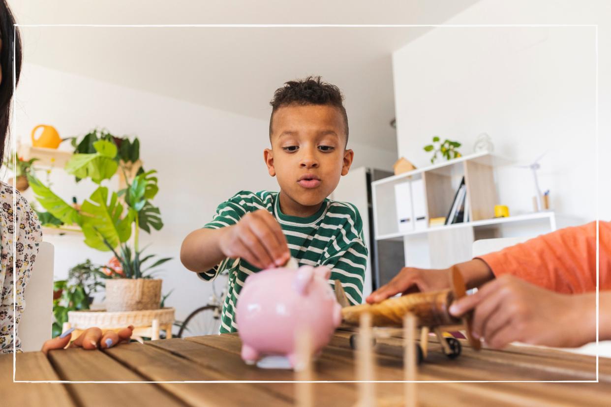  Child putting coins into a piggy bank while sitting at a dining room table at home. 