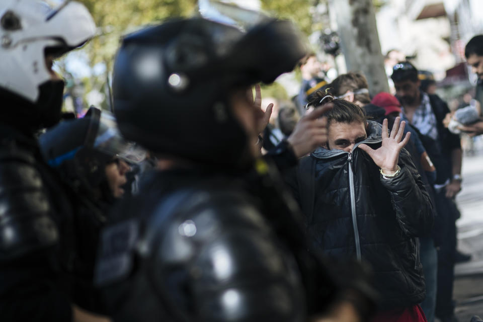 A protestor covers his face and gestures as he walks past riot police officers during a yellow vest demonstration, in Paris, Saturday, Sept 21. 2019. Paris police have used tear gas to disperse anti-government demonstrators who try to revive the yellow vest movement in protest at perceived economic injustice and French President Emmanuel Macron's government. The French capital was placed under high security as few hundred anti-government protesters started marching in the Paris streets. (AP Photo/Kamil Zihnioglu)