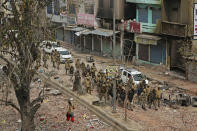 FILE- In this Thursday, Feb. 27, 2020, file photo, an Indian woman walks past as Indian paramilitary soldiers patrol a street vandalized in Tuesday's violence in New Delhi, India. Facebook in India has been selective in curbing hate speech, misinformation and inflammatory posts, particularly anti-Muslim content, according to leaked documents obtained by The Associated Press, even as the internet giant's own employees cast doubt over the motivations and interests.(AP Photo/Altaf Qadri,File)