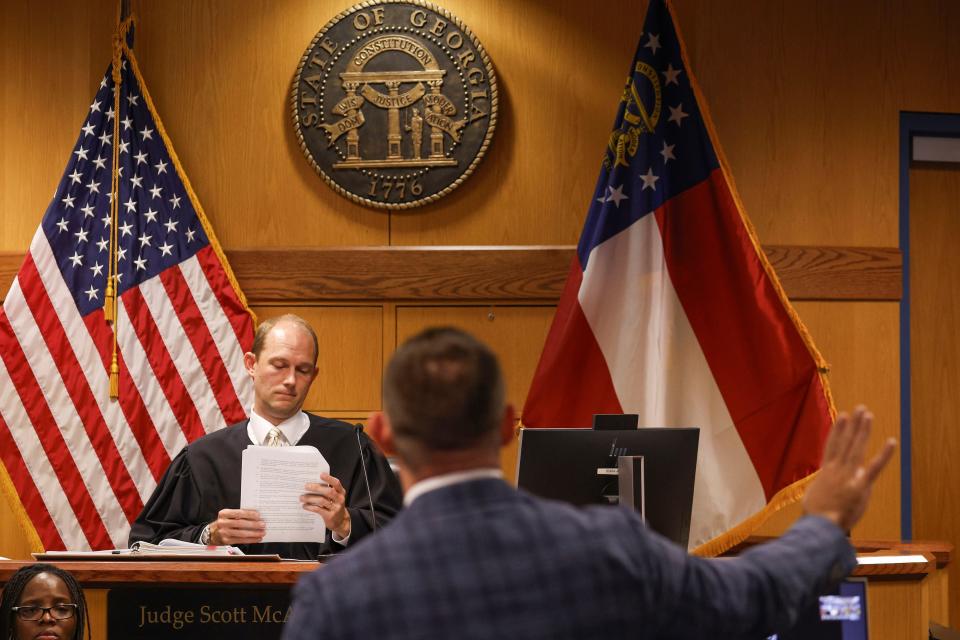 Fulton County Superior Court Judge Scott McAfee listens as Deputy District Attorney Will Wooten, right, addresses the court during a hearing on motions from defendant Sydney Powell, in Atlanta, Thursday, Oct. 5, 2023. Nineteen people, including former President Donald Trump, were indicted in August and accused of participating in a wide-ranging illegal scheme to overturn the results of the 2020 presidential election. (Erik S. Lesser/Pool Photo, via AP)