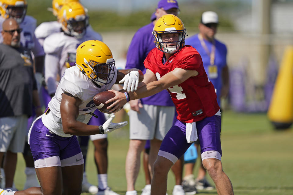 LSU quarterback Walker Howard (14) hands off to running back Noah Cain during their NCAA college football practice in Baton Rouge, La., Monday, Aug. 15, 2022. LSU quarterback Myles Brennan announced Monday that he has decided to end his college football career after five seasons with the Tigers. (AP Photo/Gerald Herbert)