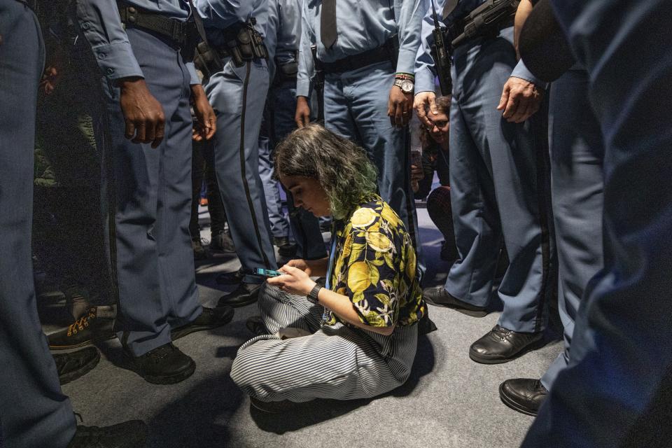 A demonstrator is surrounded by UN security staff members during a protest at the COP25 summit in Madrid, Wednesday Dec. 11, 2019. World leaders agreed in Paris four years ago to keep global warming below 2 degrees Celsius (3.6 degrees Fahrenheit), ideally no more than 1.5 C (2.7 F) by the end of the century. Scientists say countries will miss both of those goals by a wide margin unless drastic steps are taken to begin cutting greenhouse gas emissions next year. Claiming that the message doesn't seem to be getting through to governments, over one hundred activists led by representatives of indigenous peoples from Latin and North America made their way to the talks' venue, blocking for some tense minutes the entrance to a plenary meeting where U.N. Secretary General António Guterres was about to speak. (AP Photo/Bernat Armangue)