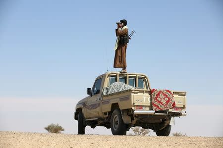 A tribal fighter loyal to Yemen's government stands on the roof of a pick-up truck as he uses binoculars to look at at Houthi positions in an area between Yemen's northern provoices of al-Jawf and Marib December 5, 2015. REUTERS/Ali Owidha