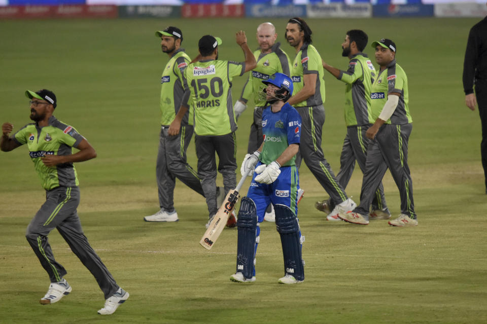 Multan Sultans batsman Adam Lyth, in blue, walks back while Lahore Qalandars pacer David Wiese, third right back, celebrate with teammates after the Lyth's dismissal during the second eliminator cricket match of Pakistan Super League T20 cup at National Stadium in Karachi, Pakistan, Sunday, Nov. 15, 2020. (AP Photo/Fareed Khan)