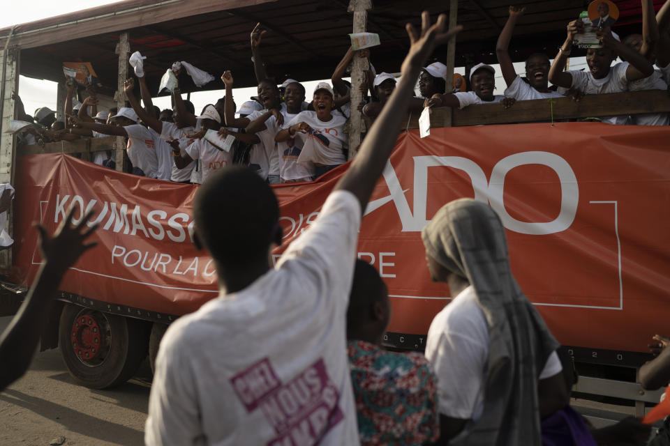 A supporter of the presidential candidate Kouadio Konan Bertin reacts as supporters of the Ivory Coast President Alassane Ouattara, ride a truck, during a final campaign rally in Abidjan, Ivory Coast, Thursday, Oct. 29, 2020. Bertin, known as KKB, has presented his candidacy as an independent candidate for the upcoming Oct. 31 election, and said he would not join the boycott proposed by two main opponents of Ivory Coast President Alassane Ouattara. (AP Photo/Leo Correa)