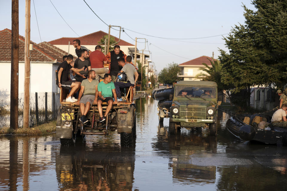 Residentes y miembros del ejército griego cruzan la localidad inundada de Palamás, en Grecia, el viernes 8 de septiembre de 2023. (AP Foto/Vaggelis Kousioras)