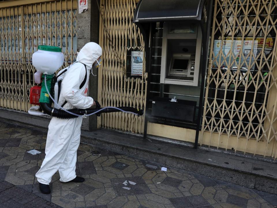 A firefighter disinfects an ATM machine to help prevent the spread of the new coronavirus in Tehran, Iran, Thursday, March 5, 2020.