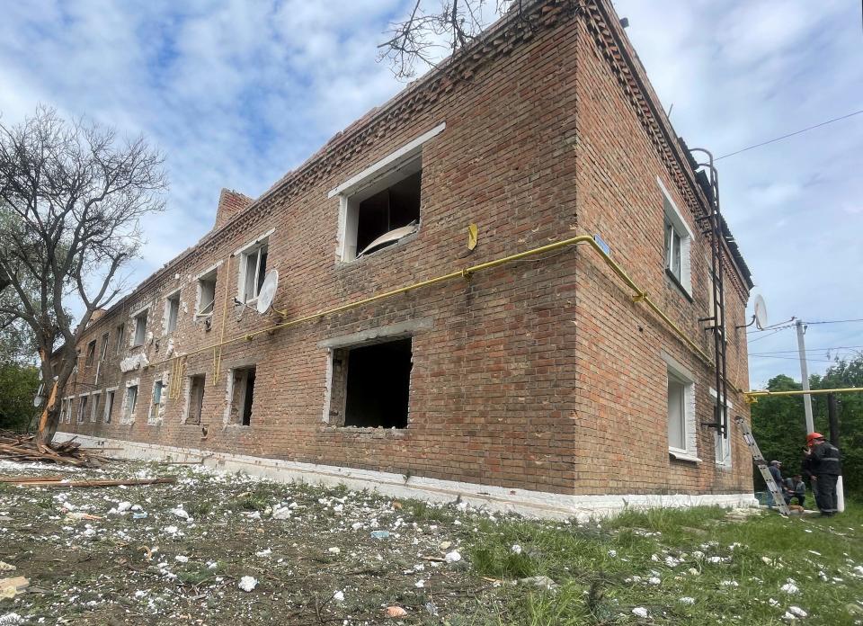 Workers stand next to a damaged residential building following a Russian strike in a small town in Dnipropetrovsk (AFP via Getty Images)