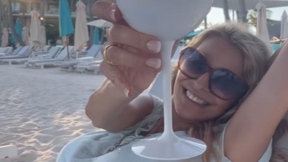 Tess cheersing a cocktail on the beach