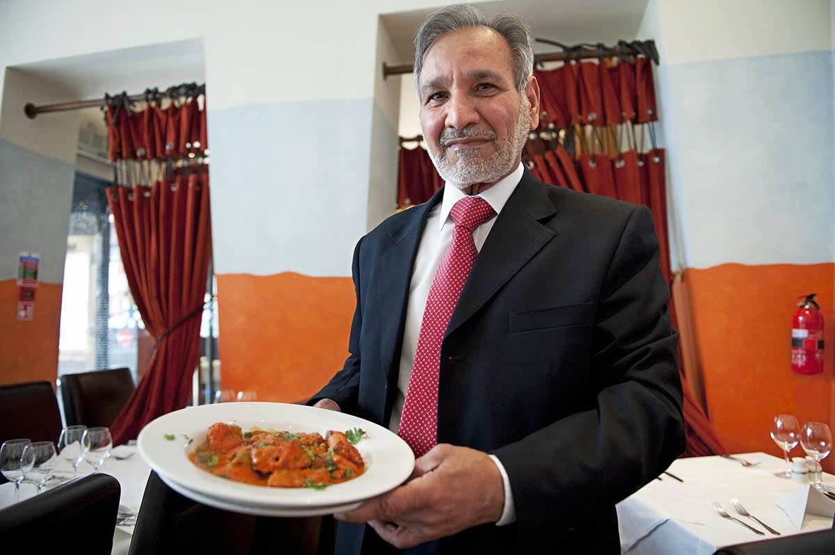 Ahmed Aslam Ali, the owner of the Shish Mahal restaurant in Glasgow, is pictured with a plate of chicken tikka masala in his restaurant in 2009 (AFP via Getty Images)