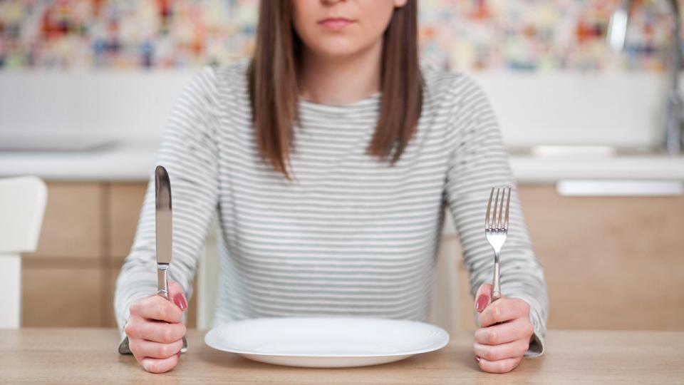 woman sits in front of an empty plate.