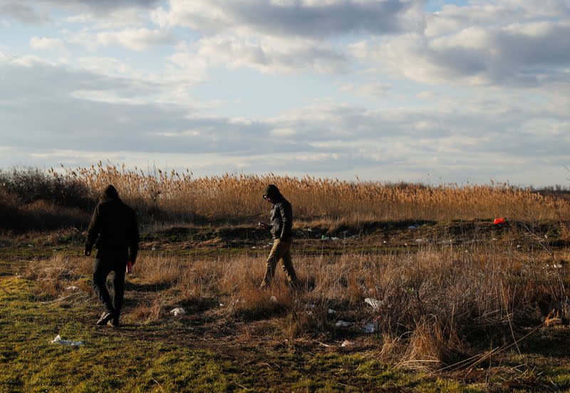 Migrants from Syria walk on a field close to the border with Hungary and Romania in the village of Majdan