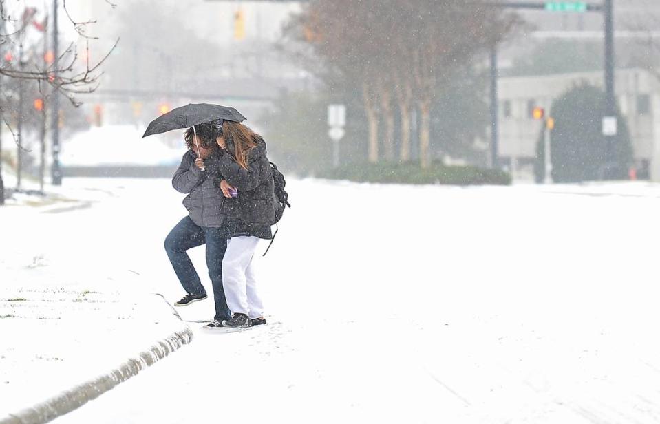Melissa and Melina Carroll of Albany, NY., cross South Caldwell Street in a wintry mix of rain, sleet and snow on Sunday, January 16, 2022. The Carrolls are in Charlotte for the cheer competition at the Charlotte Convention Center.