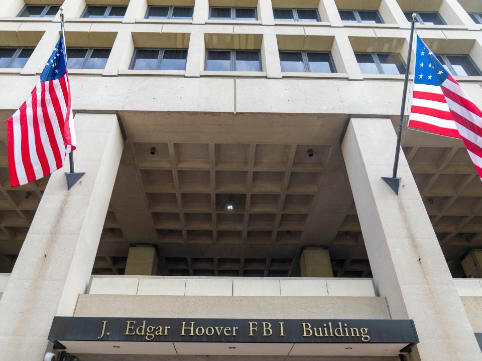 The entrance of a building with US flags outside it.