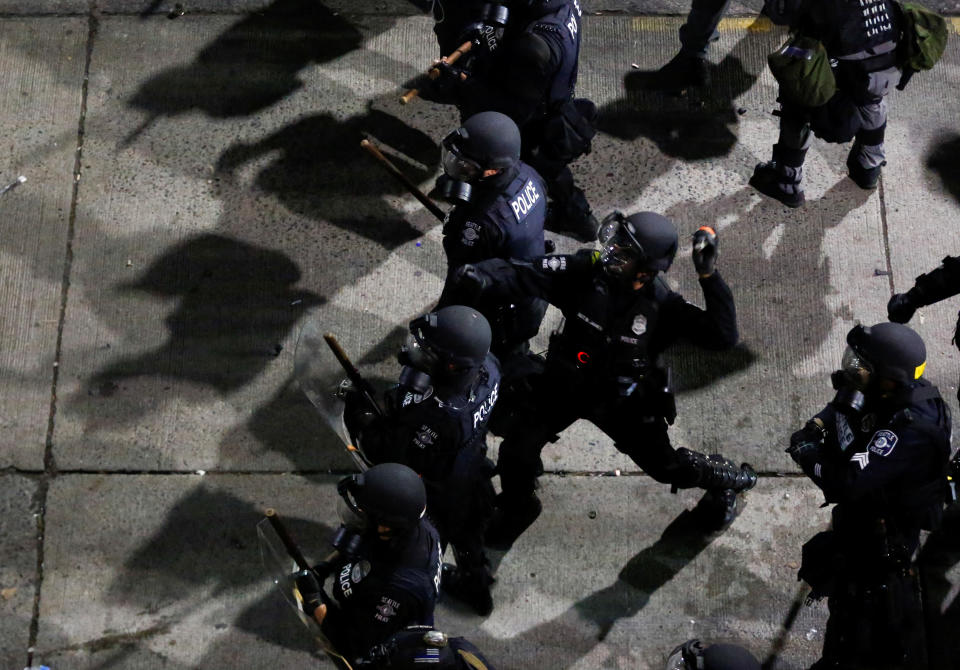 A Seattle Police officer throws a canister at protesters during a protest against racial inequality in the aftermath of the death in Minneapolis police custody of George Floyd, near the Seattle Police department's East Precinct in Seattle, Washington.