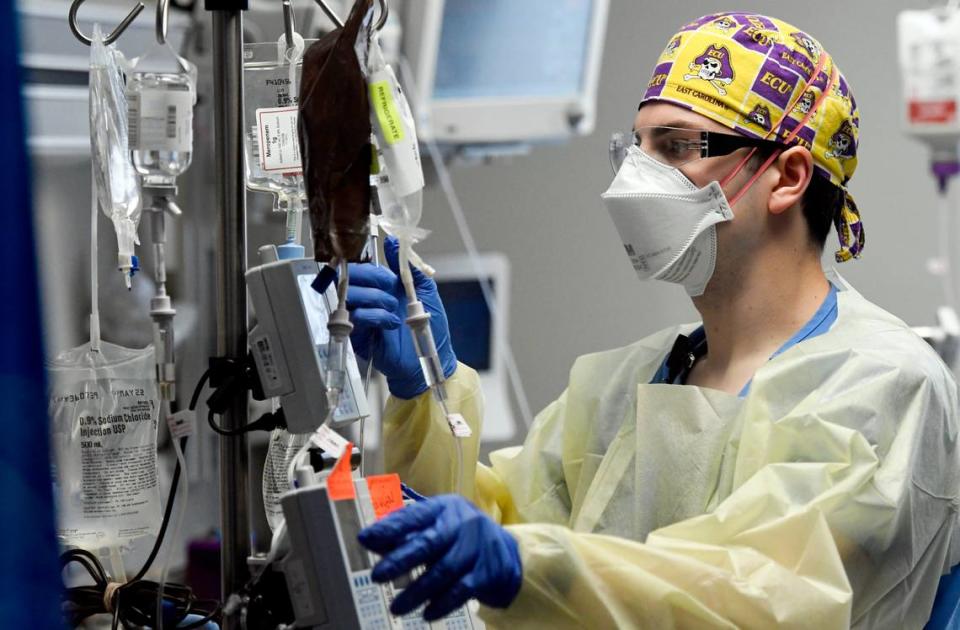 Jonathan Vitek, RN, checks numerous IV medications and fluids being administered to a COVID patient. The explosion of COVID-19 patients has helped fill beds and emergency rooms at Duke Raleigh, UNC Rex and WakeMed hospitals in Wake County.