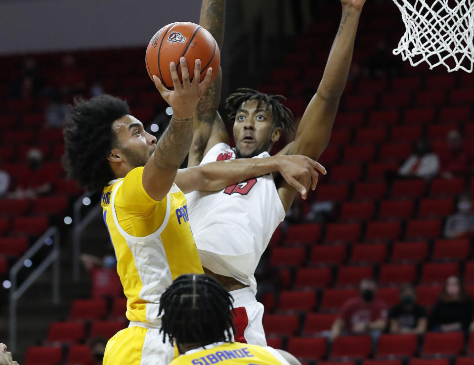 Pittsburgh's Justin Champagnie (11) heads to the basket as N.C. State's Manny Bates (15) defends during the first half of an NCAA college basketball game in Raleigh, N.C., Sunday, Feb. 28, 2021. (Ethan Hyman/The News & Observer via AP)