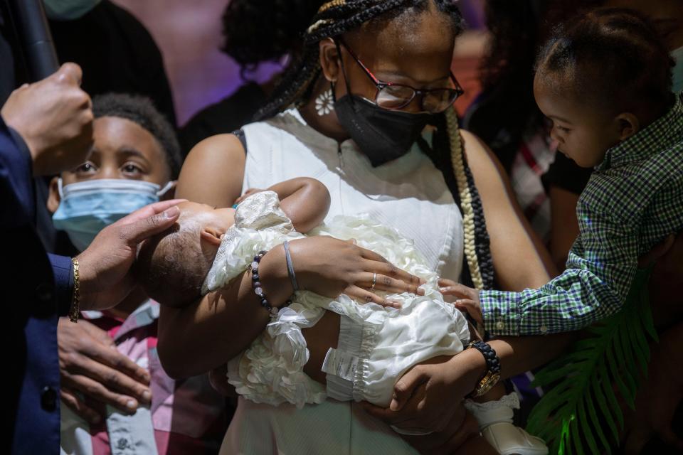 MeKiah Campbell has her baby, Amorra Campbell, dedicated by Pastor Aaron Marble while her son, Judah Campbell reaches, to his baby sister at Jefferson Street Missionary Baptist Church in Nashville , Tenn., Sunday, April 2, 2023.