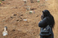 Vera Lucia Souza stands before at the gravesite of her 47-year-old brother Paulo Roberto da Silva, who died of COVID-19, during his burial at the Sao Luiz cemetery in Sao Paulo, Brazil, Thursday, June 4, 2020. (AP Photo/Andre Penner)