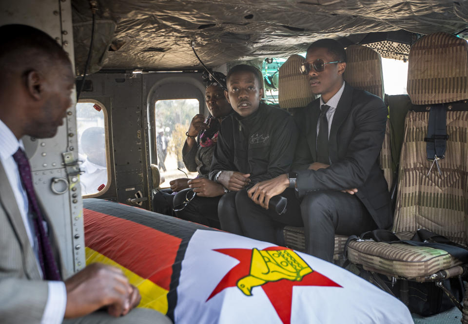 Former president Robert Mugabe's two sons Chatunga Mugabe, center, and Robert Mugabe Junior, right, accompany his casket in an air force helicopter for transport to a stadium where it will lie in state, at his official residence in the capital Harare, Zimbabwe Friday, Sept. 13, 2019. The ongoing uncertainty of the burial of Mugabe, who died last week in Singapore at the age of 95, has eclipsed the elaborate plans for Zimbabweans to pay their respects to the former guerrilla leader at several historic sites. (AP Photo/Ben Curtis)