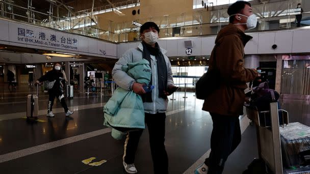 PHOTO: Travelers walk with their luggage through the Beijing Capital International Airport, Dec 27, 2022 in Beijing, China. (Tingshu Wang/Reuters)